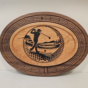 Oval wooden cribbage board with a carved golfer in mid-swing, surrounded by a scenic course and peg holes.
