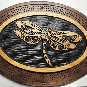 Custom wooden cribbage board with detailed dragonfly engraving on black center oval inlay