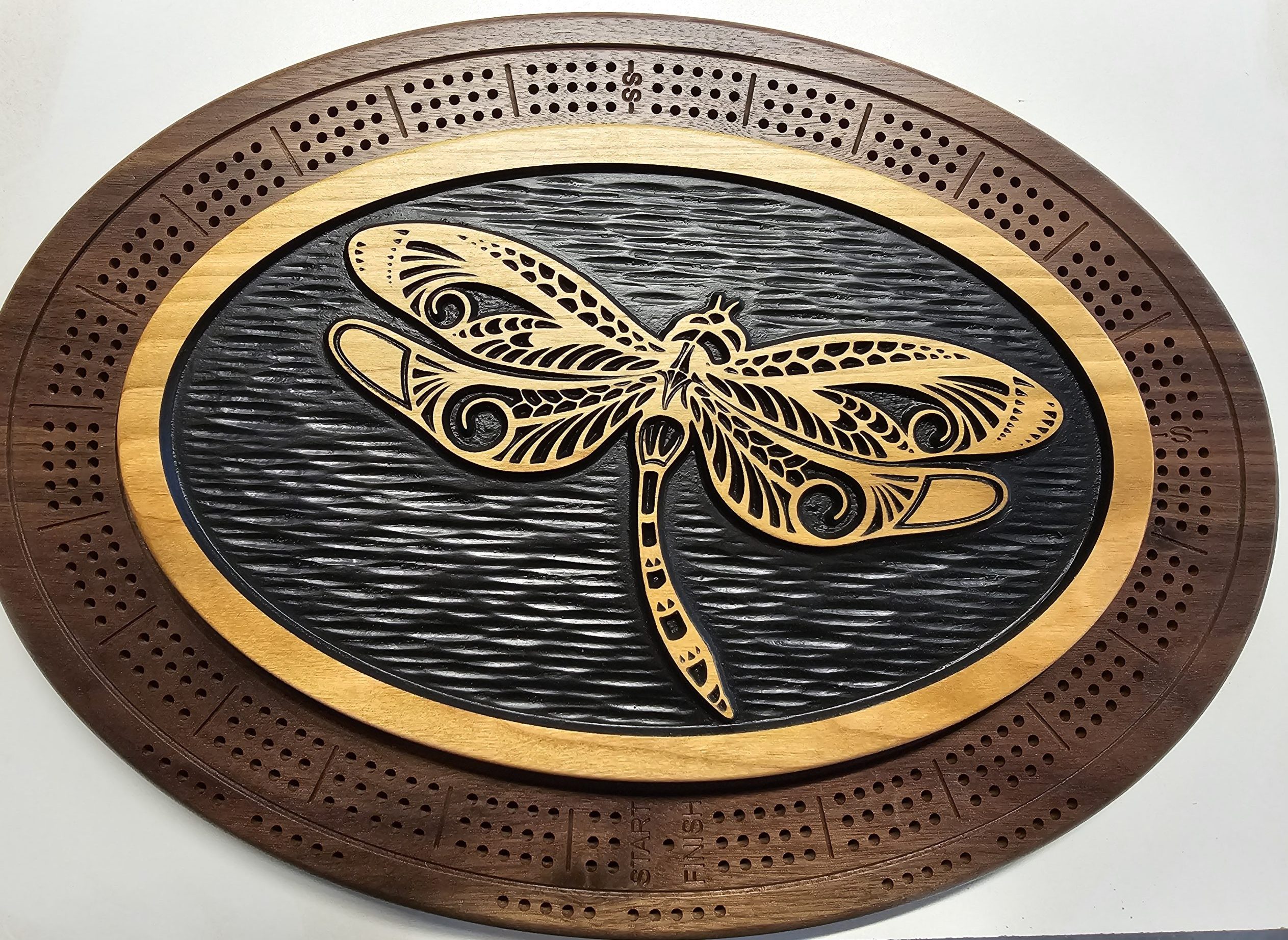 Custom wooden cribbage board with detailed dragonfly engraving on black center oval inlay